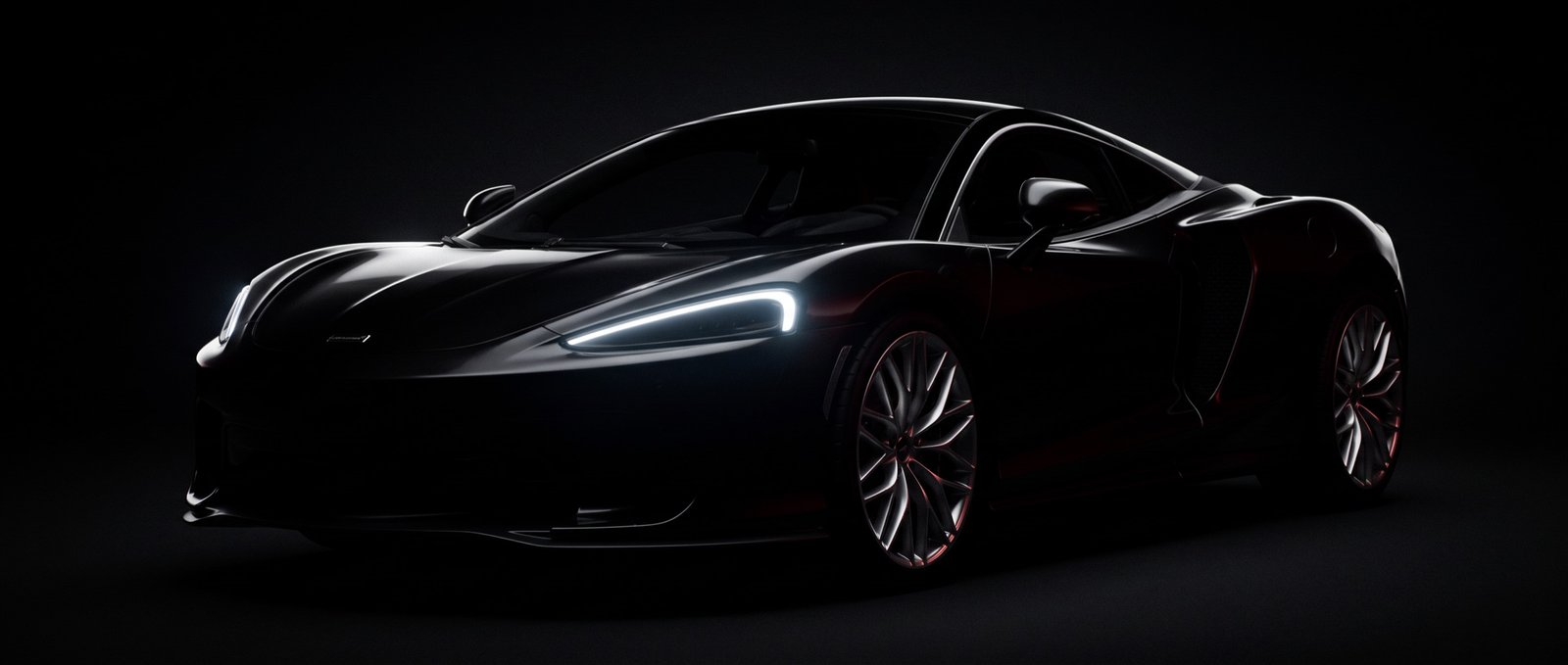 McLaren GTS preto de frente, quase invisível no escuro, só a linha dos faróis acesa