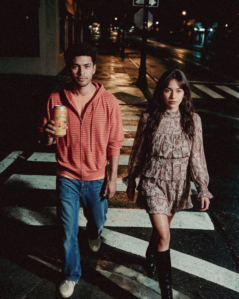 Casal a atravessar a rua à noite com uma lata na mão